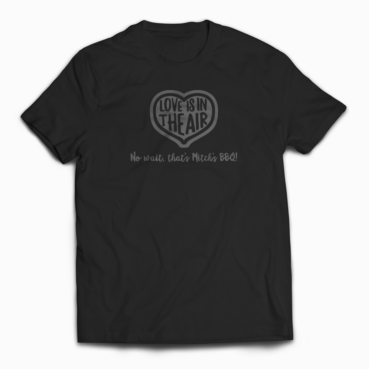 An image of a T-shirt design that says "Love is in the Air. No Wait, That's Mitch's BBQ"