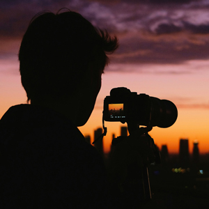 An image of a guy photographing a sunset over the city skyline
