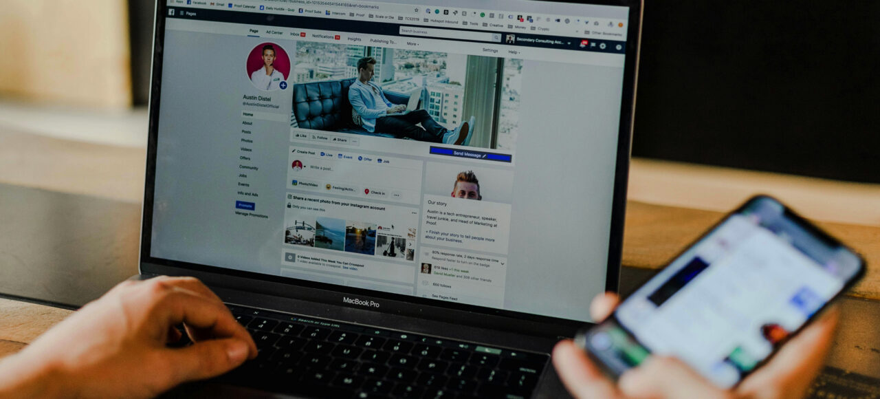 Image of a guy on his laptop with mobile phone in hand